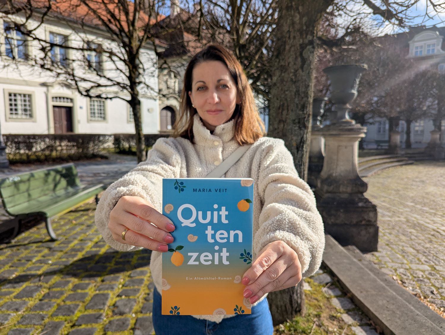 Autorin Maria Veit mit ihrem ersten Altmühltal-Roman "Quittenzeit" auf dem Residenzplatz in Eichstätt